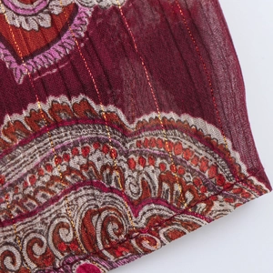 Détail d'une robe ethnique bordeaux avec des motifs cachemire et fils métalliques dorés