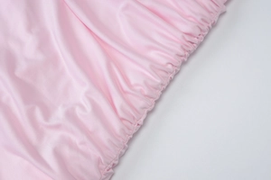 Dettaglio ravvicinato del tessuto increspato rosa con cuciture elastiche sul vestito