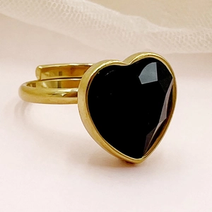 Gros plan détaillé d'une bague coeur dorée avec pierre noire et anneau ajustable