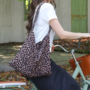 Large leopard print canvas tote bag carried by a cyclist for a stylish outdoor look