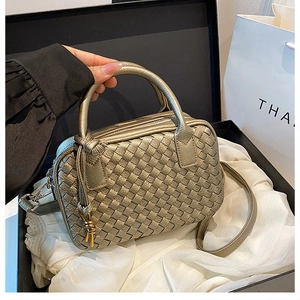 Detailed view of golden woven texture on Boston handbag with elegant handle and strap
