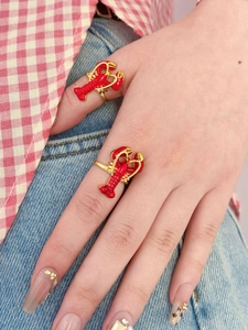 Gros plan détaillé de bagues homard rouge portées à la main pour un style marin estival unique