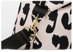 Detail of durable gold metal hook and black shoulder strap on cow print travel bag