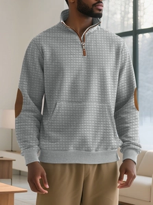 Detail of grey quilted quarter-zip sweatshirt with brown faux leather elbow patches