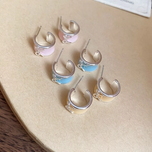 Dettaglio degli orecchini a perno in smalto pastello a forma di fiocco in rosa, blu e giallo