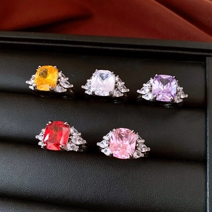 Macro view of five colorful rectangular zircon rings with pear-cut side stones on black leather
