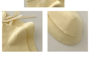 Detail showing pale yellow ribbed knit socks with elegant satin bow on the cuff
