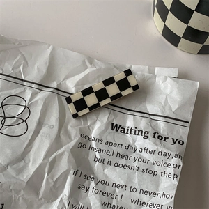 Detail of a rectangular black and white checkered hair clip on vintage paper background