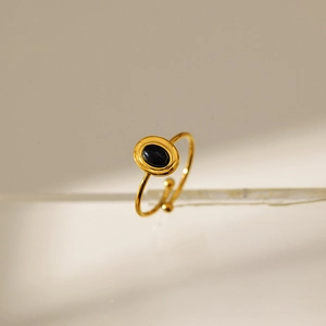 Detail of adjustable gold ring with oval black stone inlay and minimalist vintage design