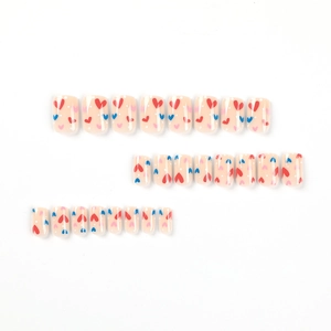 Press on nails set with heart patterns and white polka dots on a soft nude pink base