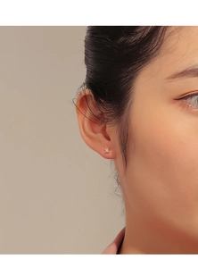 Close-up of small 14K gold star earring with zircon stone on model's ear