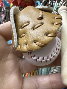 Macro shot of mini brown leather baseball glove and white ball keychain details