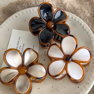 Vintage amber flower hair claws in black, white and champagne gold on a beige plate
