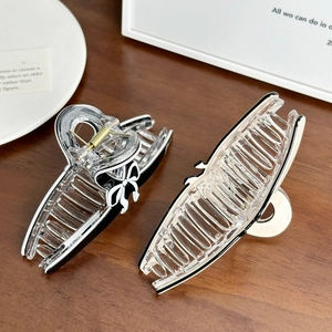 Minimalist large bow hair claw clips in black and white acrylic on a wooden table