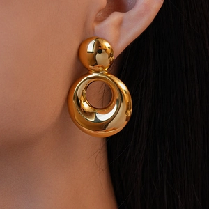 Gros plan sur des boucles d'oreilles rondes dorées à l'or 18 carats au fini poli miroir