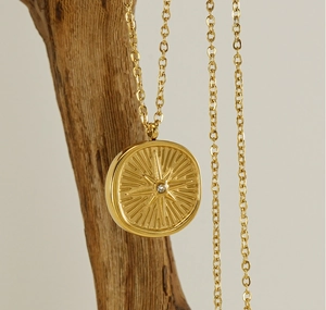 Close-up of gold starburst pendant with crystal on natural wood display stand