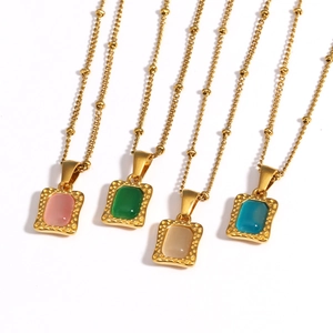 Detail van vier gouden parfumfles-hangers met roze, groene, beige en blauwe edelstenen