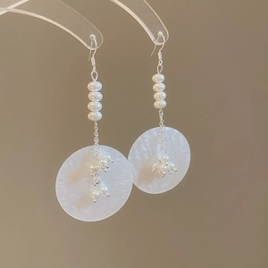 Detail of long pearl drop earrings with frosted round sequins on silver metal hooks
