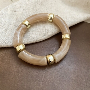 Macro view of khaki marble-textured acrylic segments with polished gold metal beads