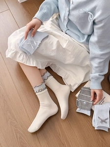 Détail de chaussettes en coton avec bords à volants, nœuds et broderies aux tons pastels