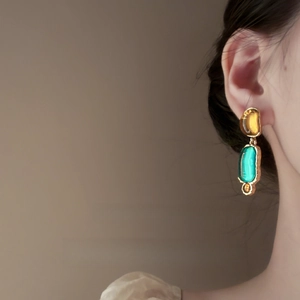 Unique irregular resin dangle earrings with gold-plated accents worn by a model