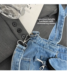 Detail of blue denim fabric texture and shiny silver metal hook fastener on shoulder bag
