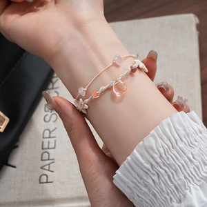 Detail of woven bracelets with colorful drop charms and starfish on model wrist