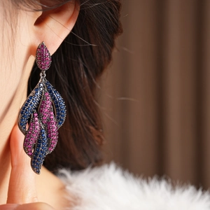 Macro detail of teardrop earrings with pink and blue zircons on black metal finish