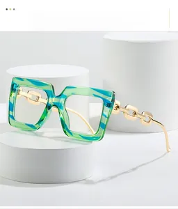 Close-up of square glasses with green-blue marbled frames and gold chain metal temples