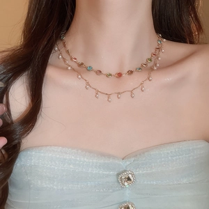 Nahaufnahme der zweilagigen Goldkette mit bunten Edelsteinen und kleinen Perlenanhängern