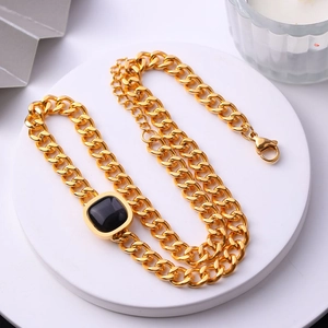 Vue détaillée du collier gourmette doré avec pendentif carré en pierre noire sur support blanc