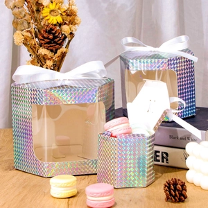 Detailed view of holographic hexagonal gift boxes with window and white ribbon on wooden table
