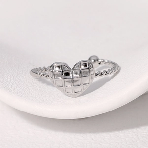 Adjustable silver heart ring with checkered embossed pattern and twisted band on tray