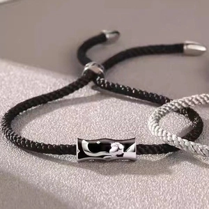Dettaglio del bracciale a cordoncino nero intrecciato a mano con ciondolo d'argento