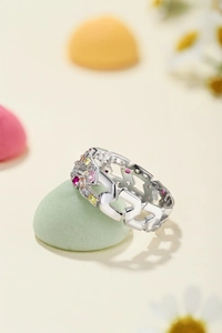 Macro detail of silver ring featuring geometric chain design and multi-color gemstones