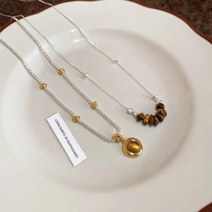 Macro shot of tiger eye stone bead necklaces on white porcelain and brown fabric