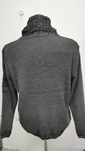Dettaglio del maglione grigio scuro con collo alto e polsini con trama mista bianco e nero