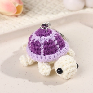 Close-up of handmade crochet turtle keychain with purple striped shell and knitted texture