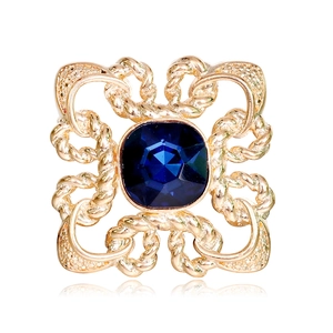 Square gold knot brooch with a deep blue crystal center on a clean white background