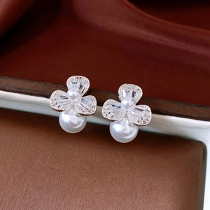 Close-up of floral stud earrings with clear crystals and white pearls on brown box