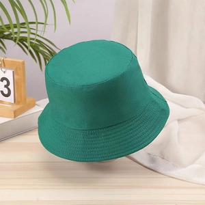 Detail shot of a dark green cotton bucket hat on a wooden desk with decorative greens