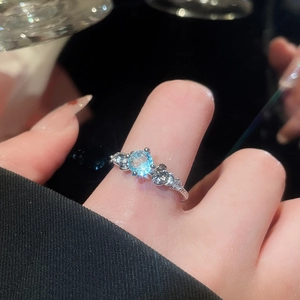Macro shot of silver ring featuring a light blue gemstone with white diamond accents