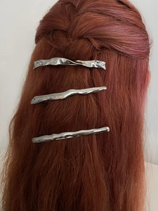 Detail of three silver irregular wave pattern hair clips on a woman's ponytail