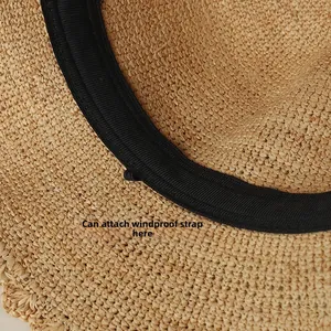 Detail view of woven straw hat interior featuring a practical black sweatband with a wind rope loop