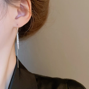 Close-up of elegant silver tassel drop earrings with sparkling zircon on a model