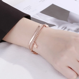Double-layered rose gold snake chain bracelet with star charms worn on a wrist