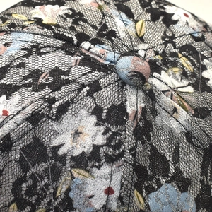Détail de la casquette à fleurs avec dentelle noire et paillettes argentées brillantes