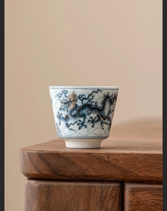 Macro detail of blue and white dragon pattern on high-end ceramic tea cup with gold accents