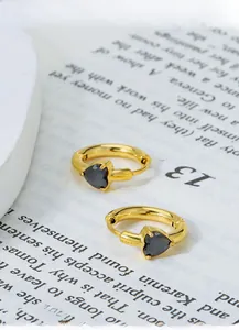 Detail of heart-shaped gold titanium earrings with black zircon on vintage book