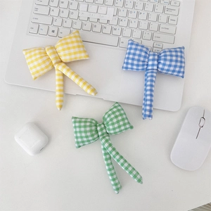 Three colorful checkered bow hair accessories on a desk with a white laptop and mouse